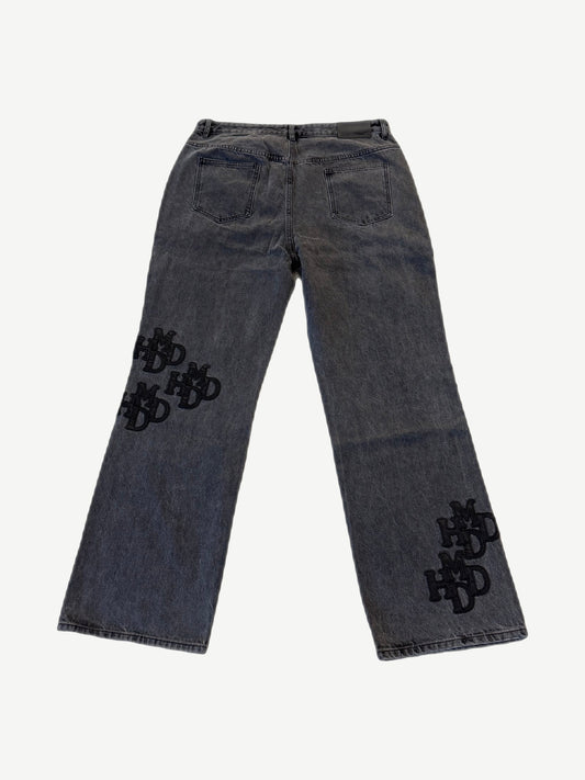 HMDD gray patch pants back view with black HMDD monogram embroidered patches concentrated on left lower leg.