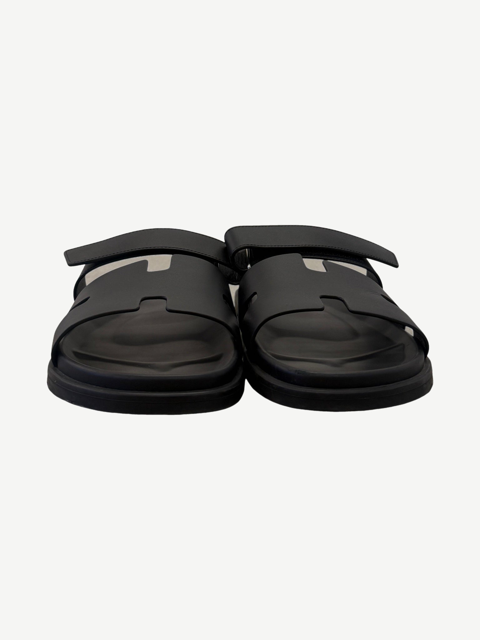 Hermes Chypre sandal pair front view in noir black calfskin, showing H-cutout vamp and adjustable ankle strap.