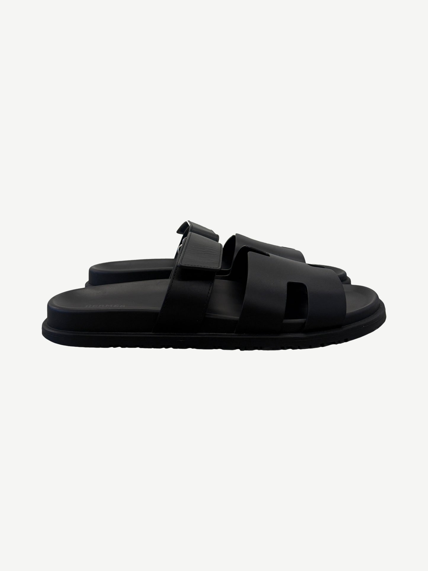 Hermes Chypre sandal in noir black calfskin side profile with adjustable strap and cleated rubber outsole.
