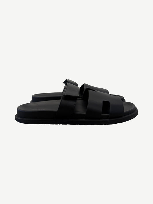 Hermes Chypre sandal in noir black calfskin side profile with adjustable strap and cleated rubber outsole.