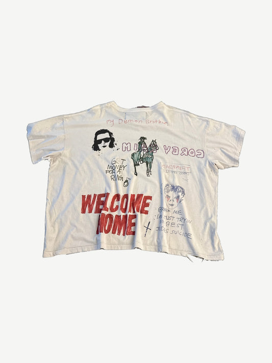 Paly Hollywood off-white tee back with red Welcome Home text, cowboy on horse, Trinidad and Judas Suicide scrawls.