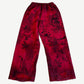 Balenciaga red baggy sweatpants back view with allover black graffiti tag print and distressed holes near hems.