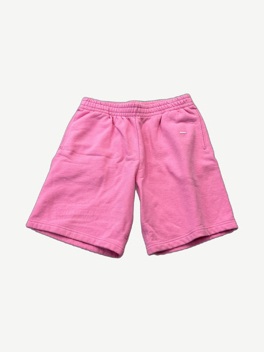 Supreme pink small box logo sweatshorts front view with red Supreme tag near hem on bright pink fleece