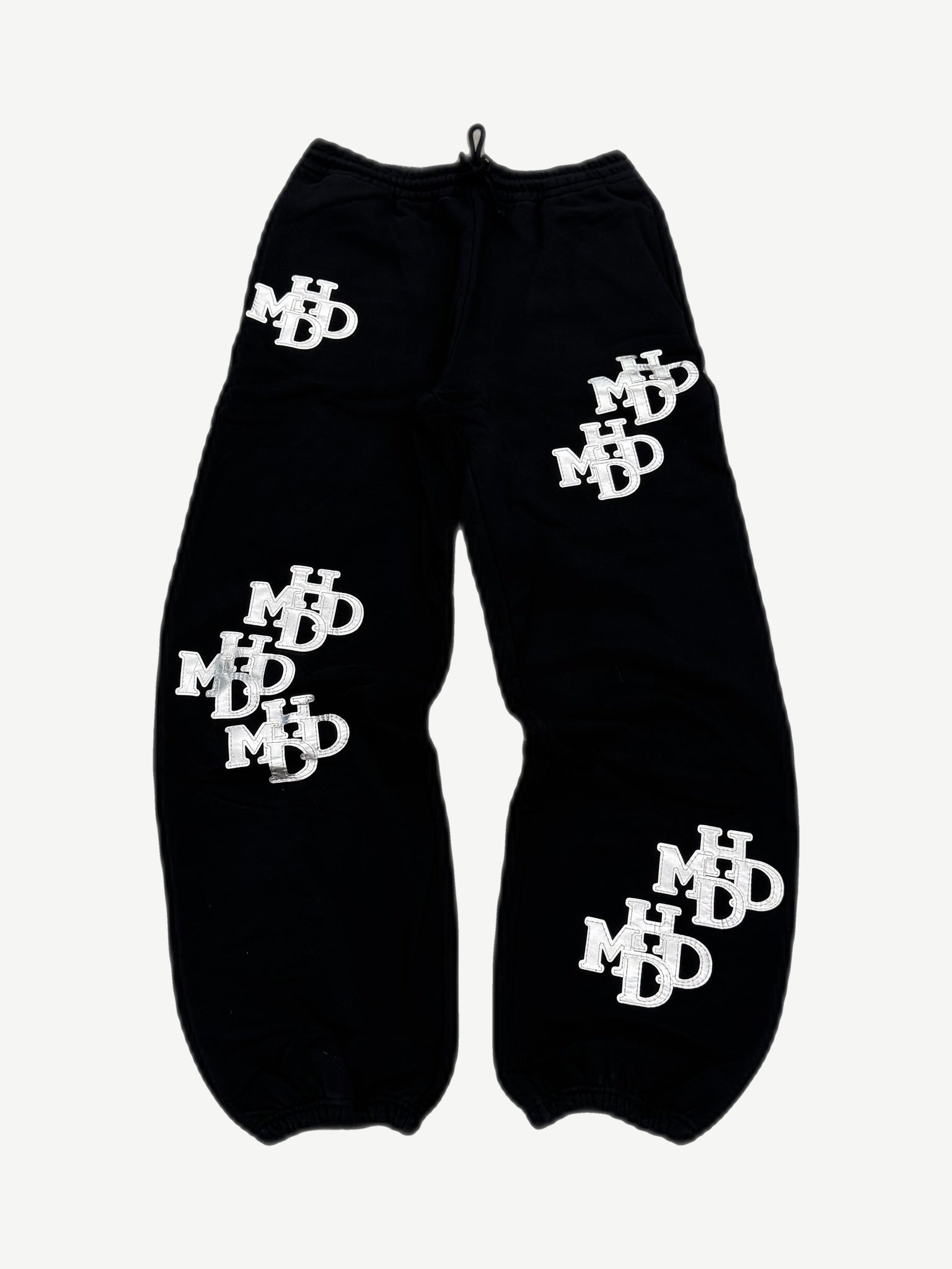 HMDD black sweatpants with all-over silver monogram patches, Happy Memories Don't Die joggers