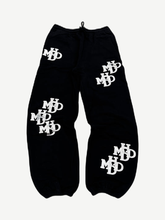 HMDD black sweatpants with all-over silver monogram patches, Happy Memories Don't Die joggers
