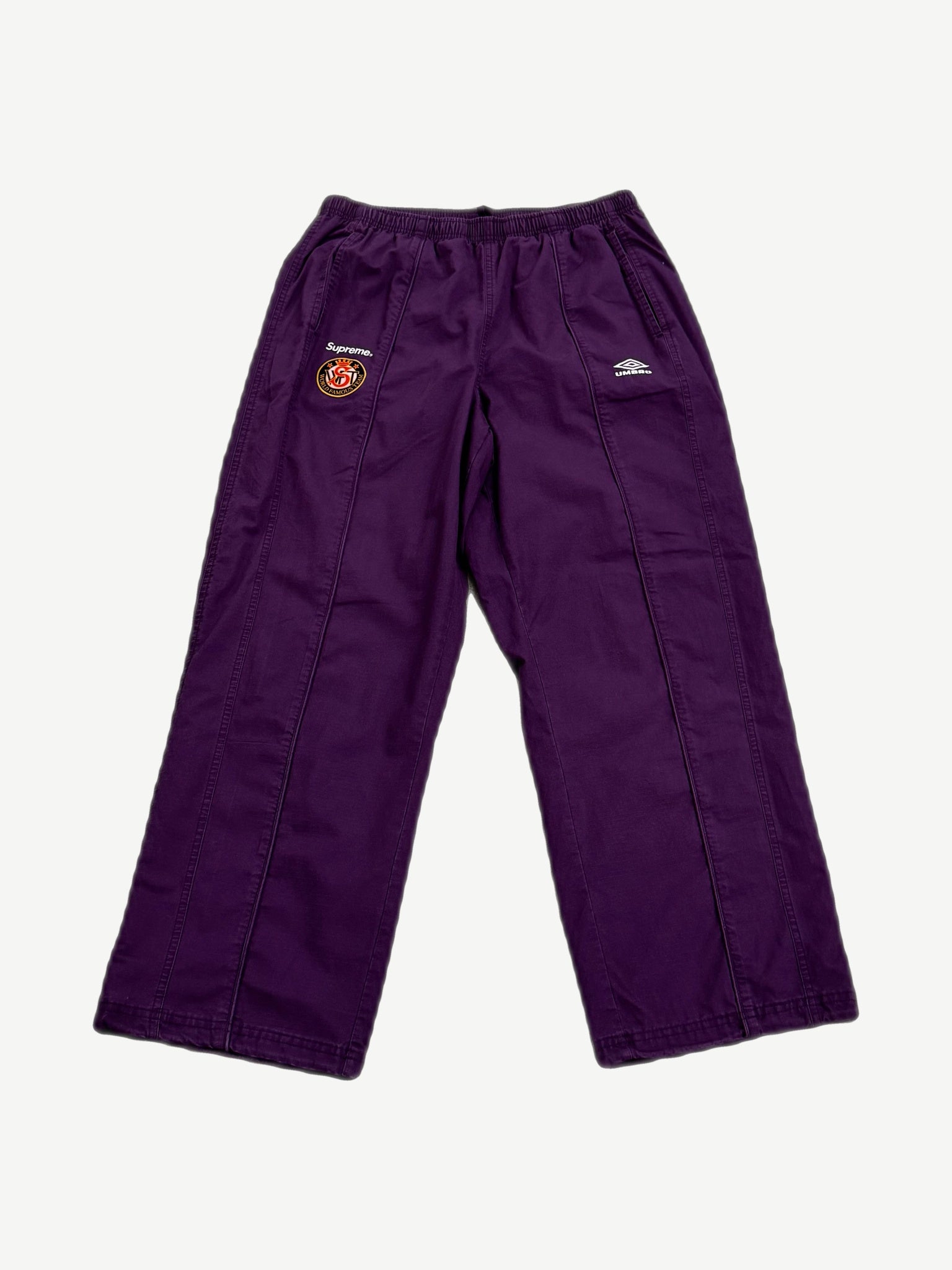 Supreme x Umbro plum cotton ripstop track pants front with Supreme World Famous crest and Umbro diamond logo.