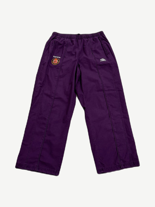 Supreme x Umbro plum cotton ripstop track pants front with Supreme World Famous crest and Umbro diamond logo.