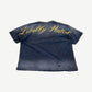 Back of Project GR washed navy tee with Locally Hated yellow cursive script print across shoulders