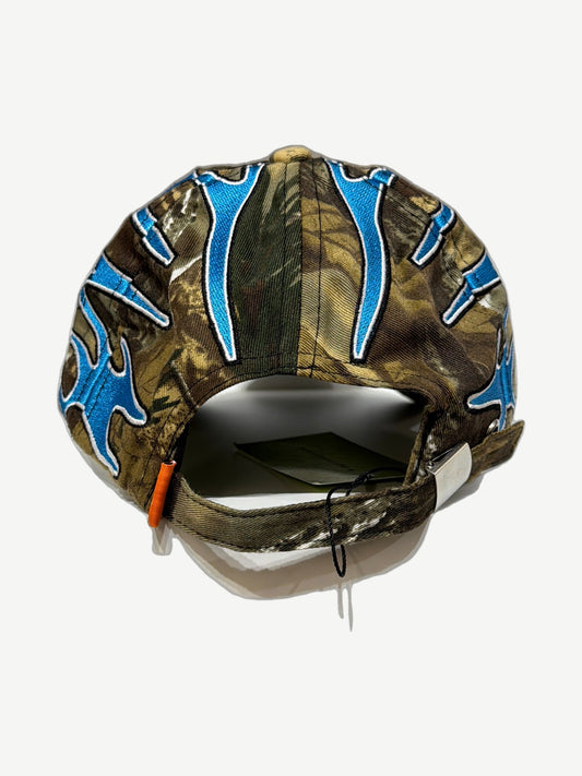 Living Product camo dad hat rear view with blue tribal flame embroidery, orange strap tab and adjustable buckle closure