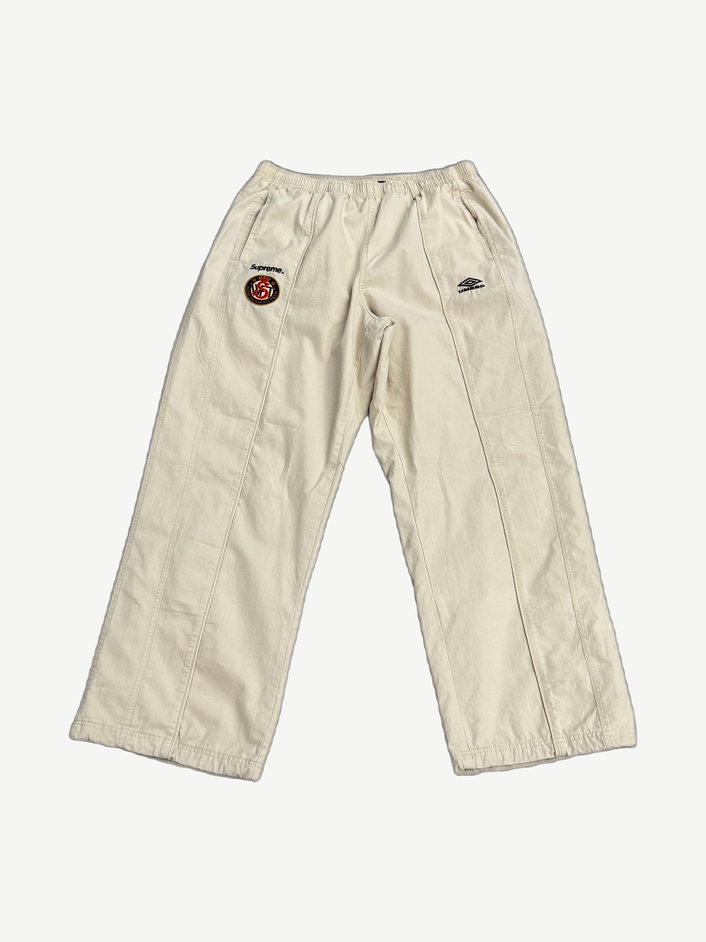 Supreme x Umbro stone cotton ripstop track pant front, wide leg with Supreme World Famous crest patch on thigh.