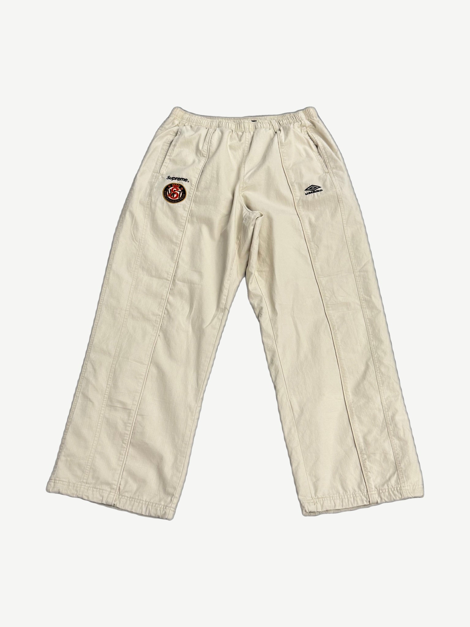 Supreme x Umbro stone cotton ripstop track pant front, wide leg with Supreme World Famous crest patch on thigh.