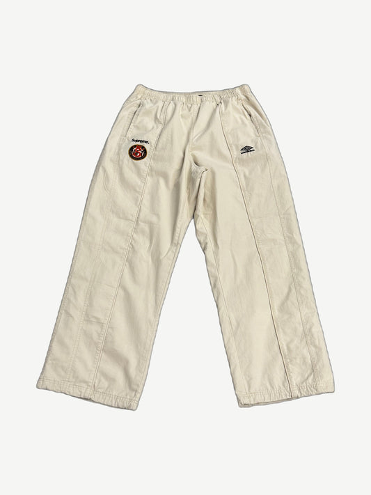 Supreme x Umbro stone cotton ripstop track pant front, wide leg with Supreme World Famous crest patch on thigh.