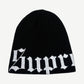 Supreme black ribbed knit beanie with large white Old English script logo wrapping the lower cuff