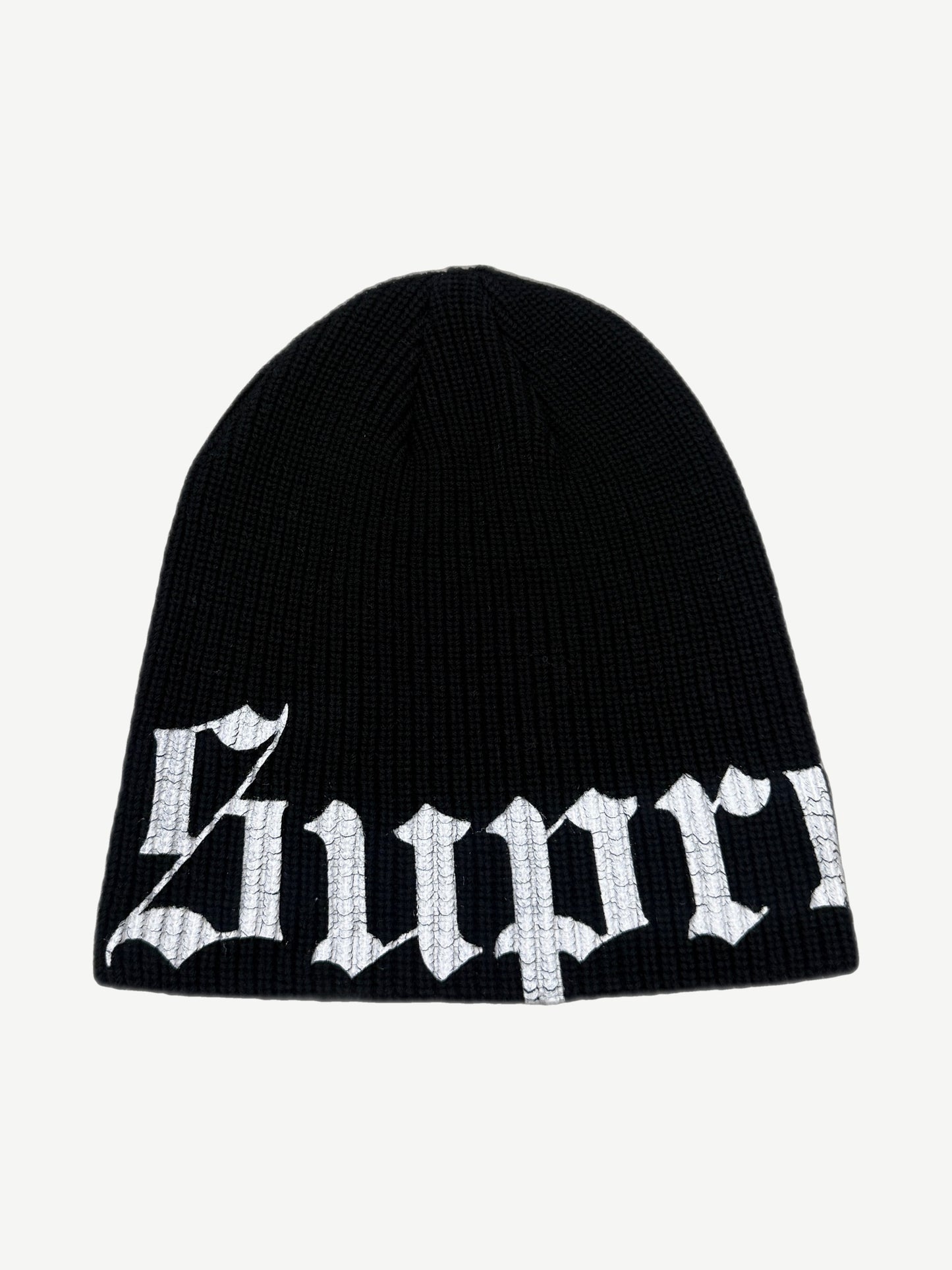 Supreme black ribbed knit beanie with large white Old English script logo wrapping the lower cuff