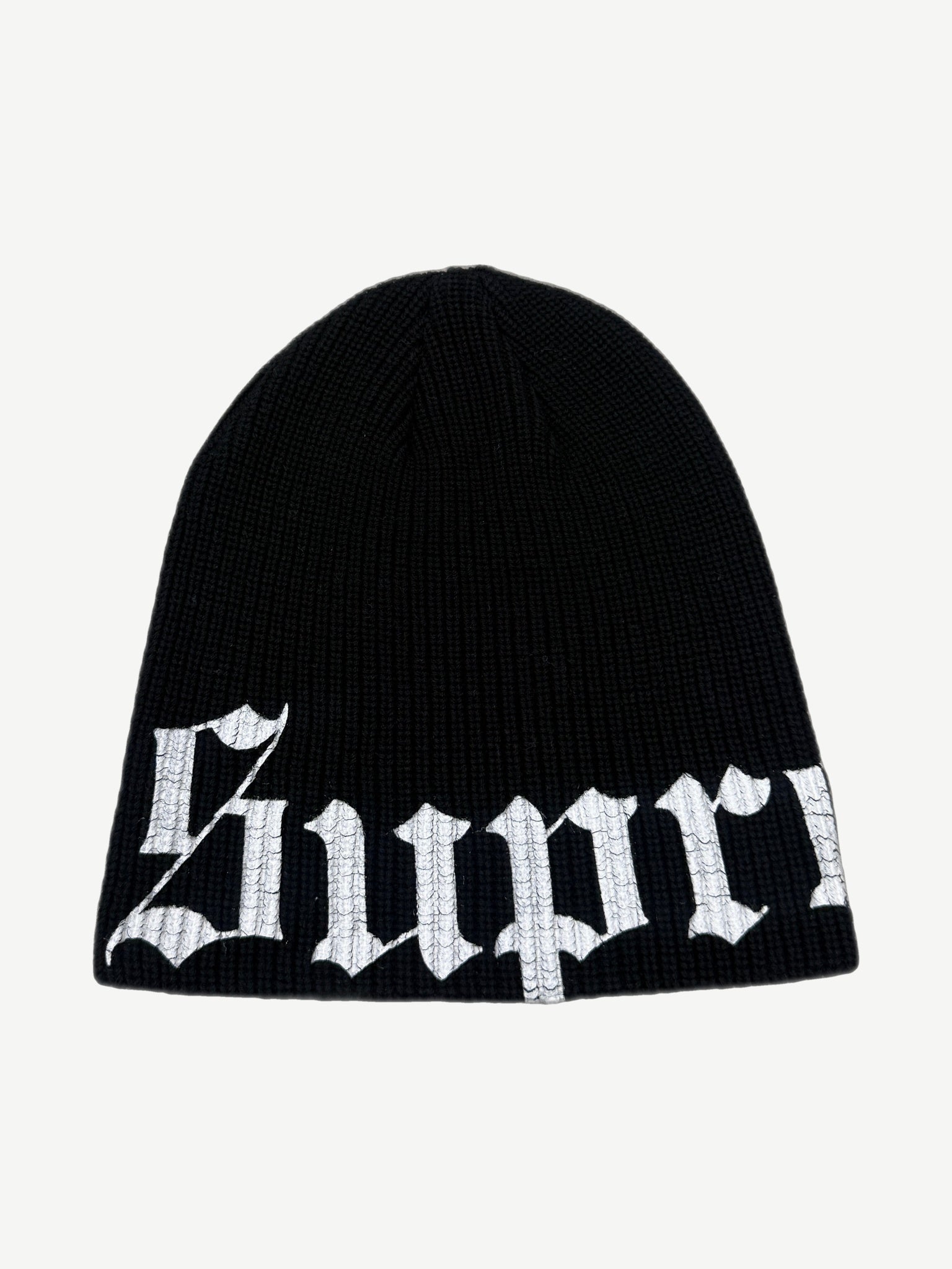 Supreme black ribbed knit beanie with large white Old English script logo wrapping the lower cuff