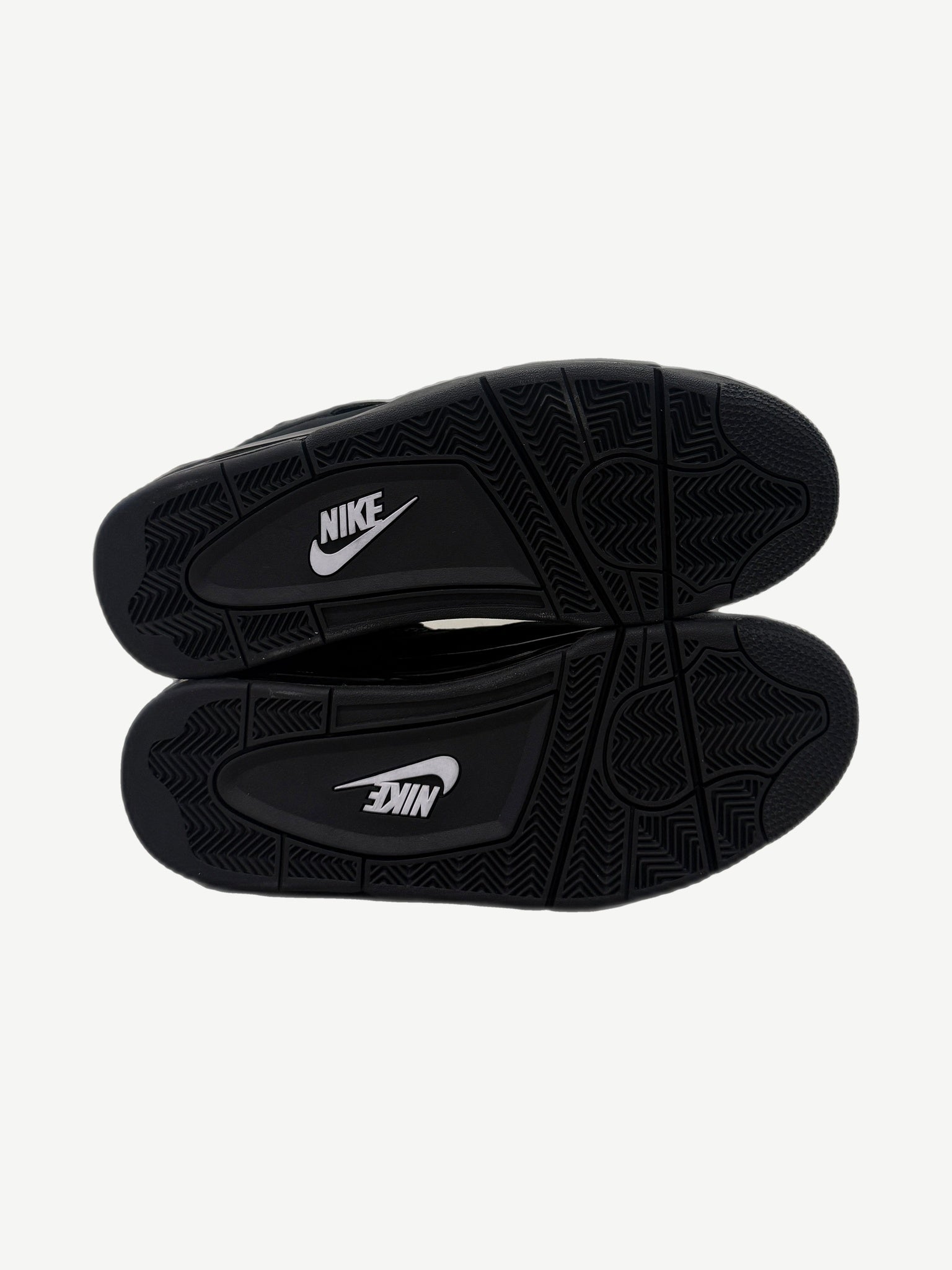 Outsole view of Air Jordan 4 Black Cat 2025 with black rubber tread and white Nike branding on midfoot pivot