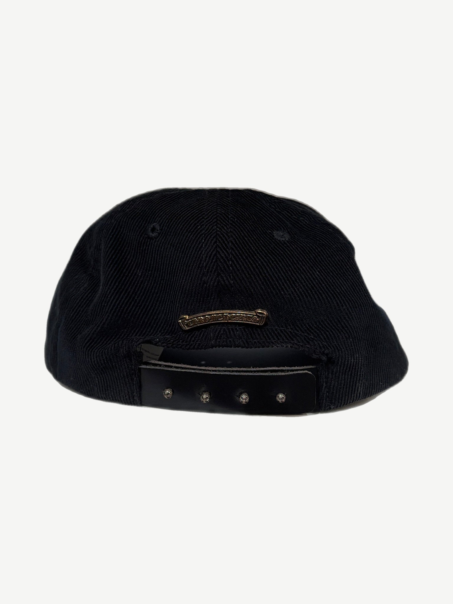 Chrome Hearts black corduroy cap angled view showing blue dagger crest and curved bill silhouette.
