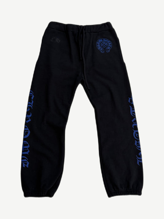 Chrome Hearts black sweatpants front view with blue horseshoe logo at waist and gothic text down both legs