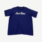Louis Vuitton royal blue tee front with white cursive Louis Vuitton signature script logo across chest.