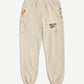 Gallery Dept cream sweatpants front view with black logo center thigh and multicolor paint splatter detailing