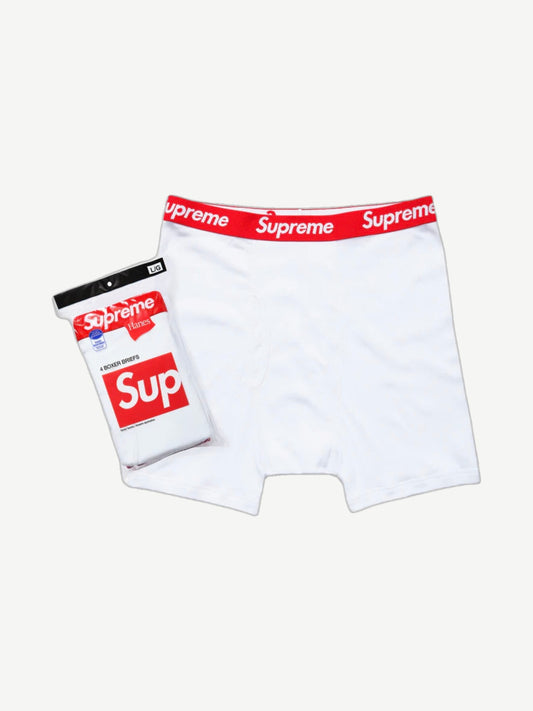 Supreme x Hanes white boxer brief with red Supreme logo waistband shown next to sealed 4-pack retail packaging.