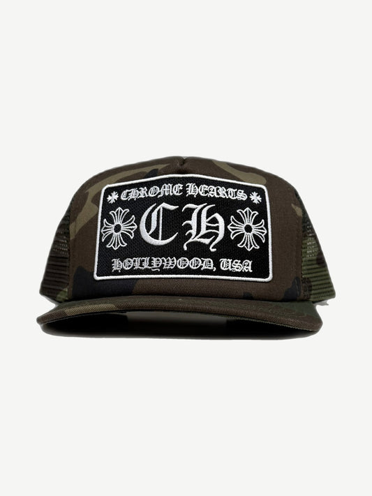 Chrome Hearts camo trucker hat with CHROME HEARTS CH HOLLYWOOD USA patch and curved camouflage bill.