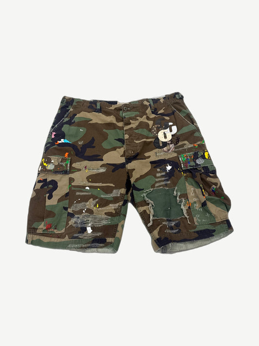 Gallery Dept green camo cargo shorts with painted white G patch on front leg, distressed hem detail