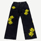 Happy Memories Don't Die HMDD black carpenter pants with yellow patches, utility loops and tool pockets, front