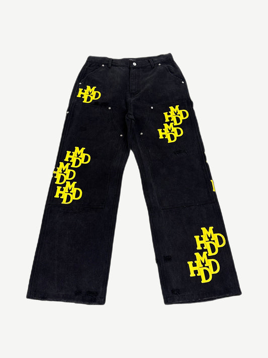 Happy Memories Don't Die HMDD black carpenter pants with yellow patches, utility loops and tool pockets, front