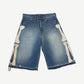 Kapital blue denim jorts front, mid-wash with embroidered cream bone appliques running down both leg sides.