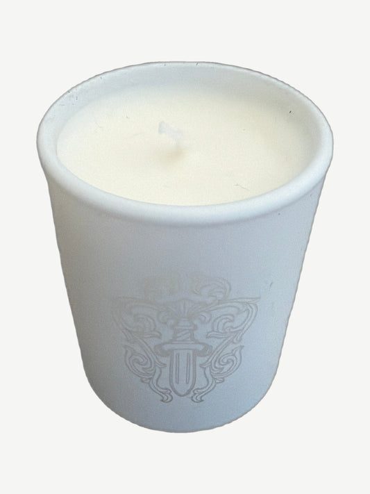 Chrome Hearts scented candle close up showing white ceramic vessel with engraved dagger crest motif.