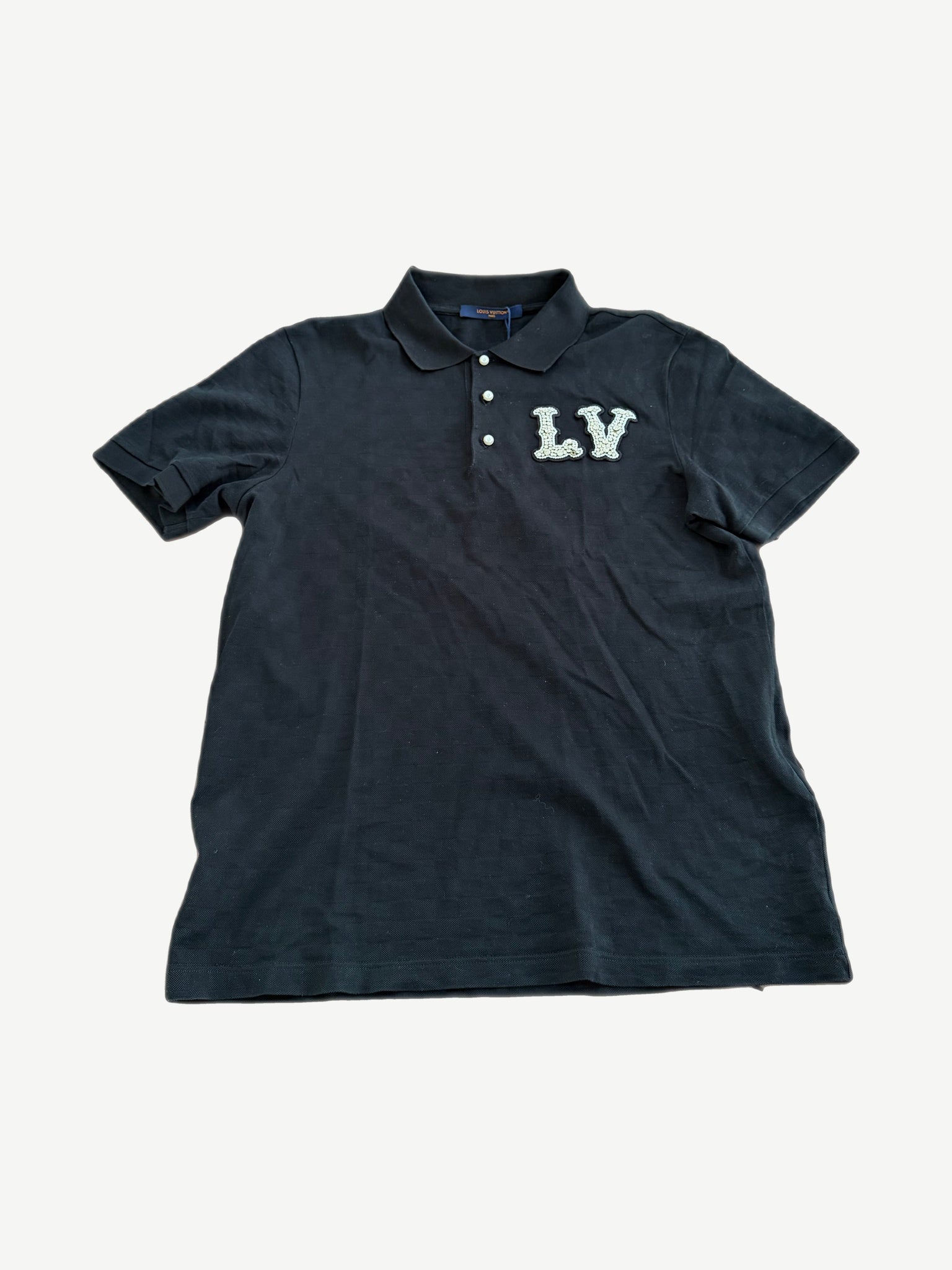 Louis Vuitton black polo with pearl LV monogram chest patch, tonal checkerboard texture and three button placket.
