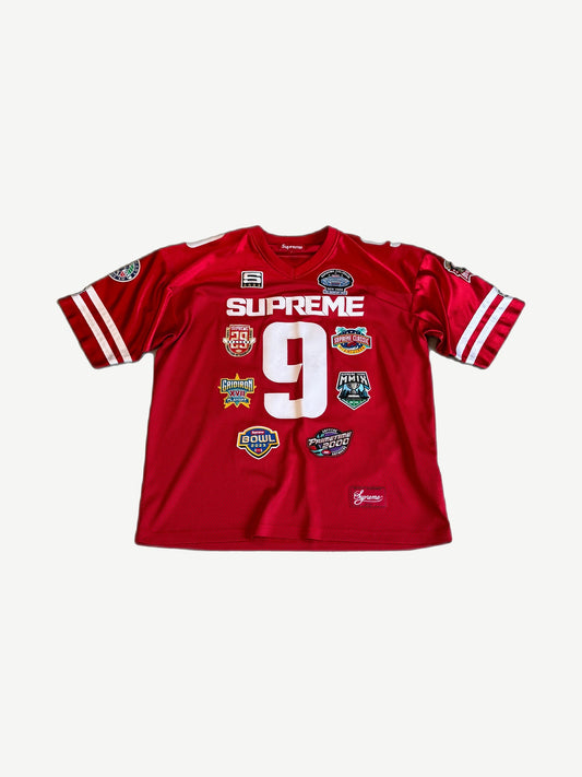 Supreme red Championships football jersey front view with embroidered chest graphics and athletic mesh fabric