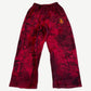 Balenciaga red baggy sweatpants front with allover black graffiti print and embroidered gold lion crest on right hip.