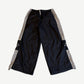 HMDD Holy nylon trackpants in black and gray with HMDD side leg print, cross logo thigh and contrast piping.