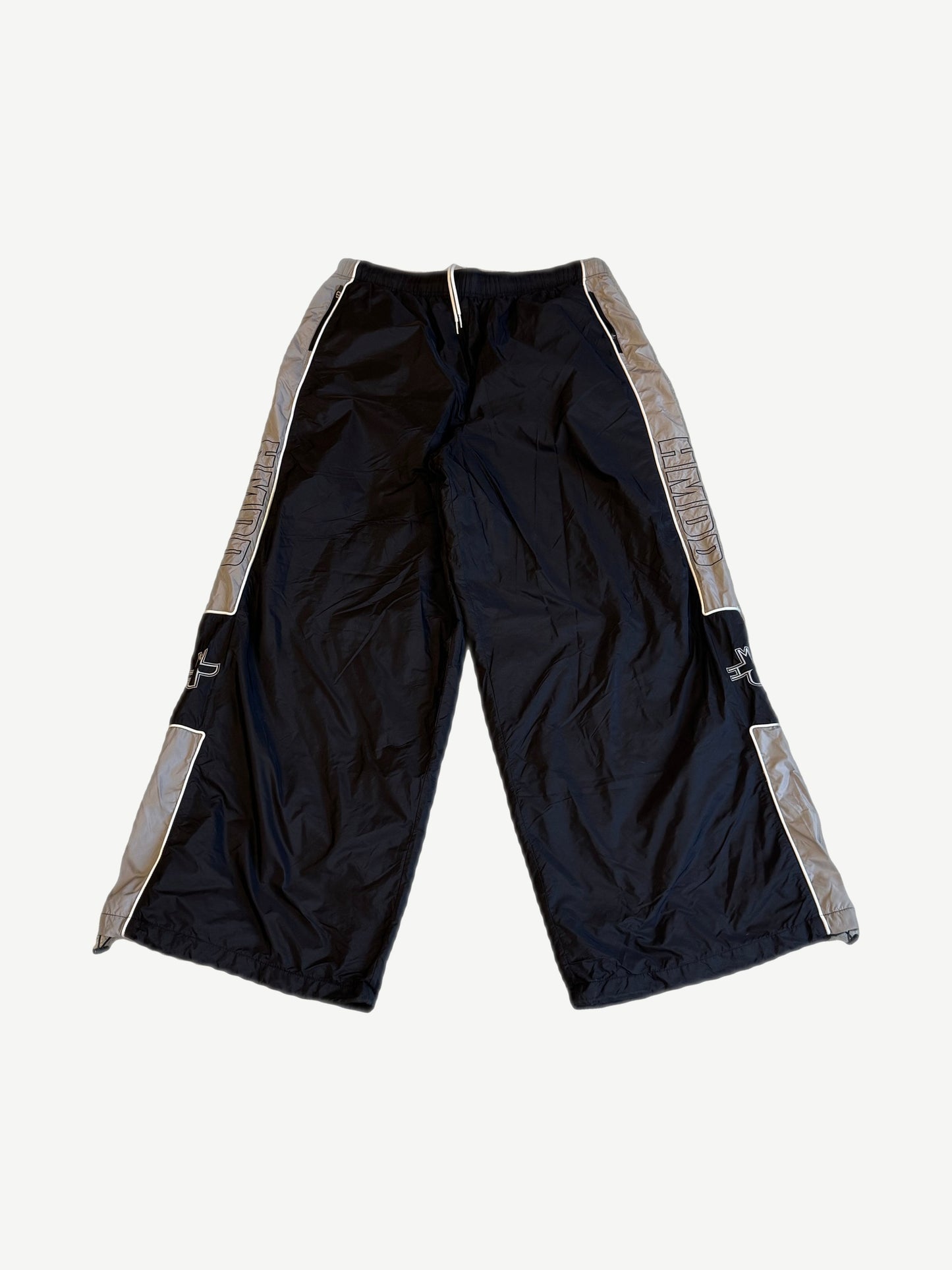 HMDD Holy nylon trackpants in black and gray with HMDD side leg print, cross logo thigh and contrast piping.