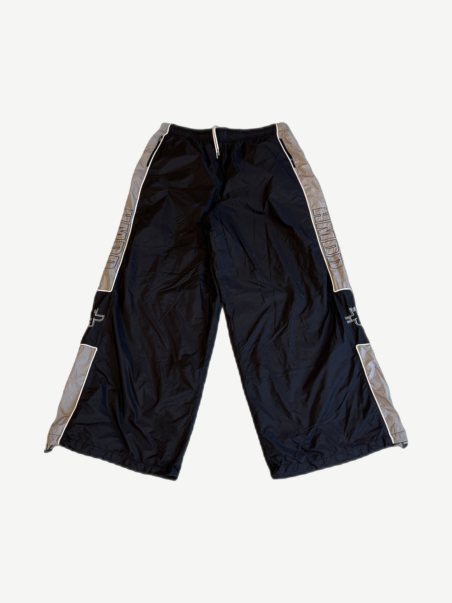 HMDD Holy nylon trackpants in black and gray with HMDD side leg print, cross logo thigh and contrast piping.