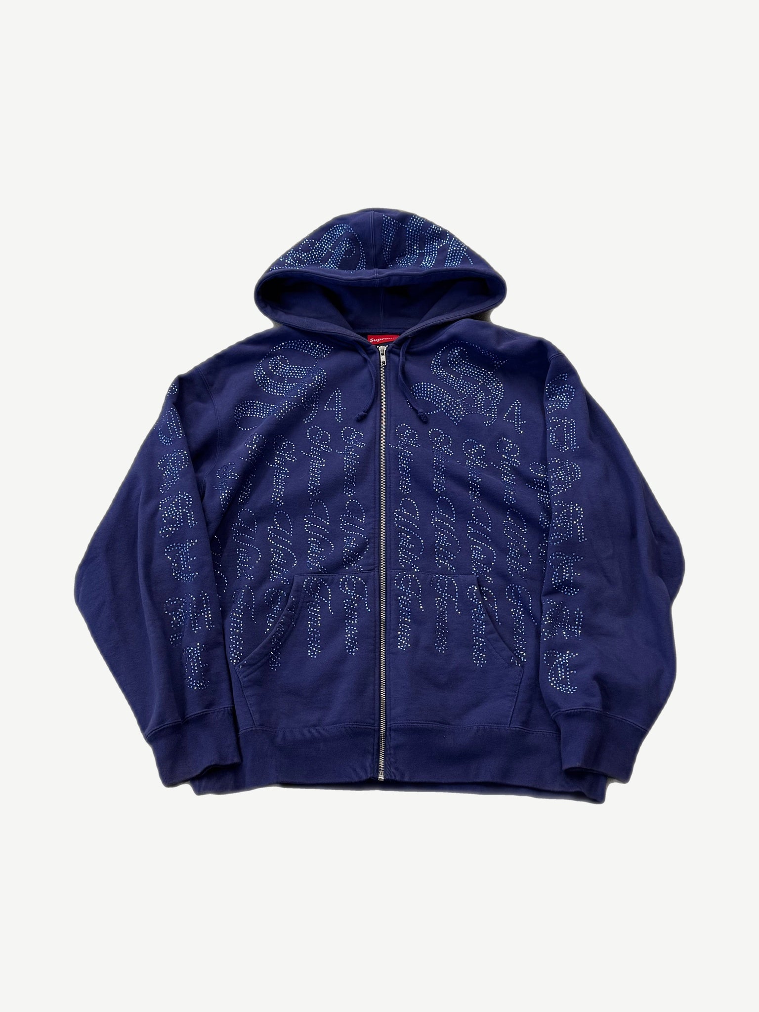 Supreme washed navy full-zip hoodie front with all-over rhinestone Supreme script logo print and box logo tab