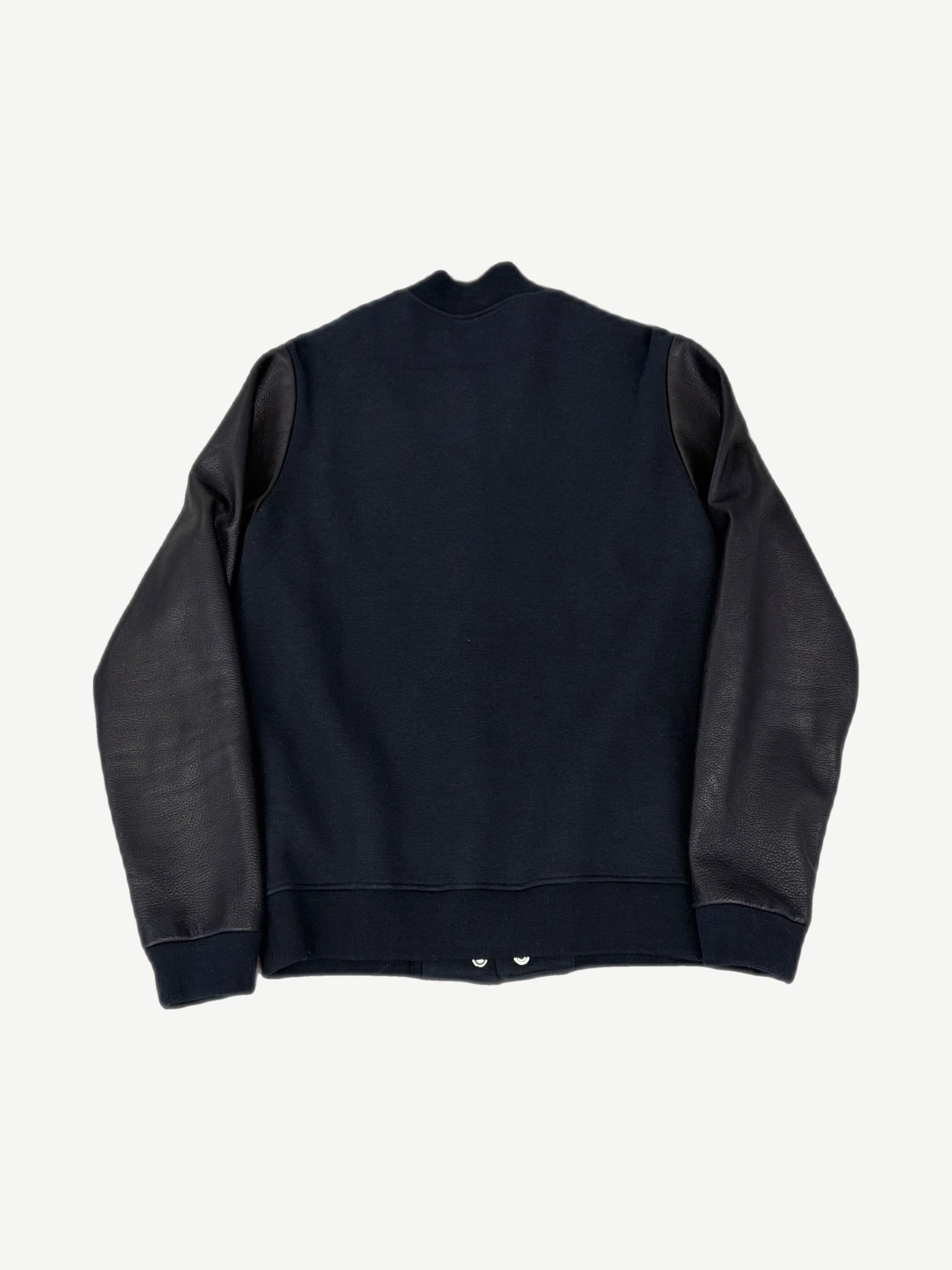 Back view of Chrome Hearts varsity jacket in navy wool with black leather raglan sleeves and ribbed cuffs