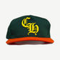 Chrome Hearts Miami baseball hat front, forest green crown with yellow Old English CH embroidery and orange brim.