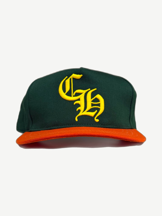 Chrome Hearts Miami baseball hat front, forest green crown with yellow Old English CH embroidery and orange brim.