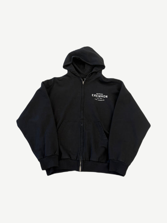 Balenciaga black Erewhon zip-up hoodie with red and white Erewhon Market logo print on chest.