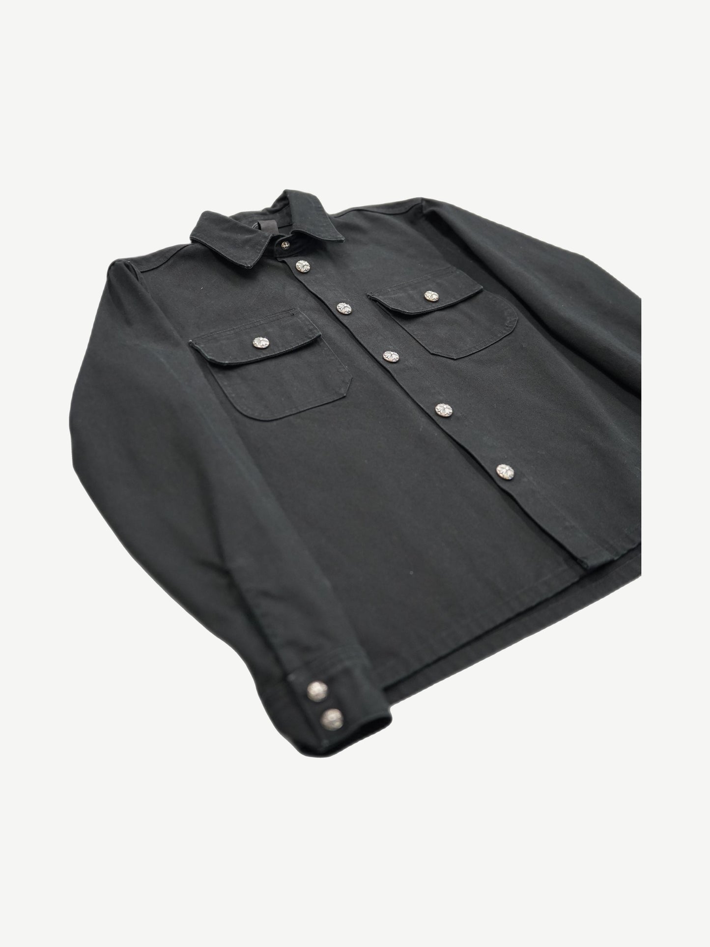 Chrome Hearts Work Dog jacket angled flat lay highlighting silver cross button placket and cuff hardware.