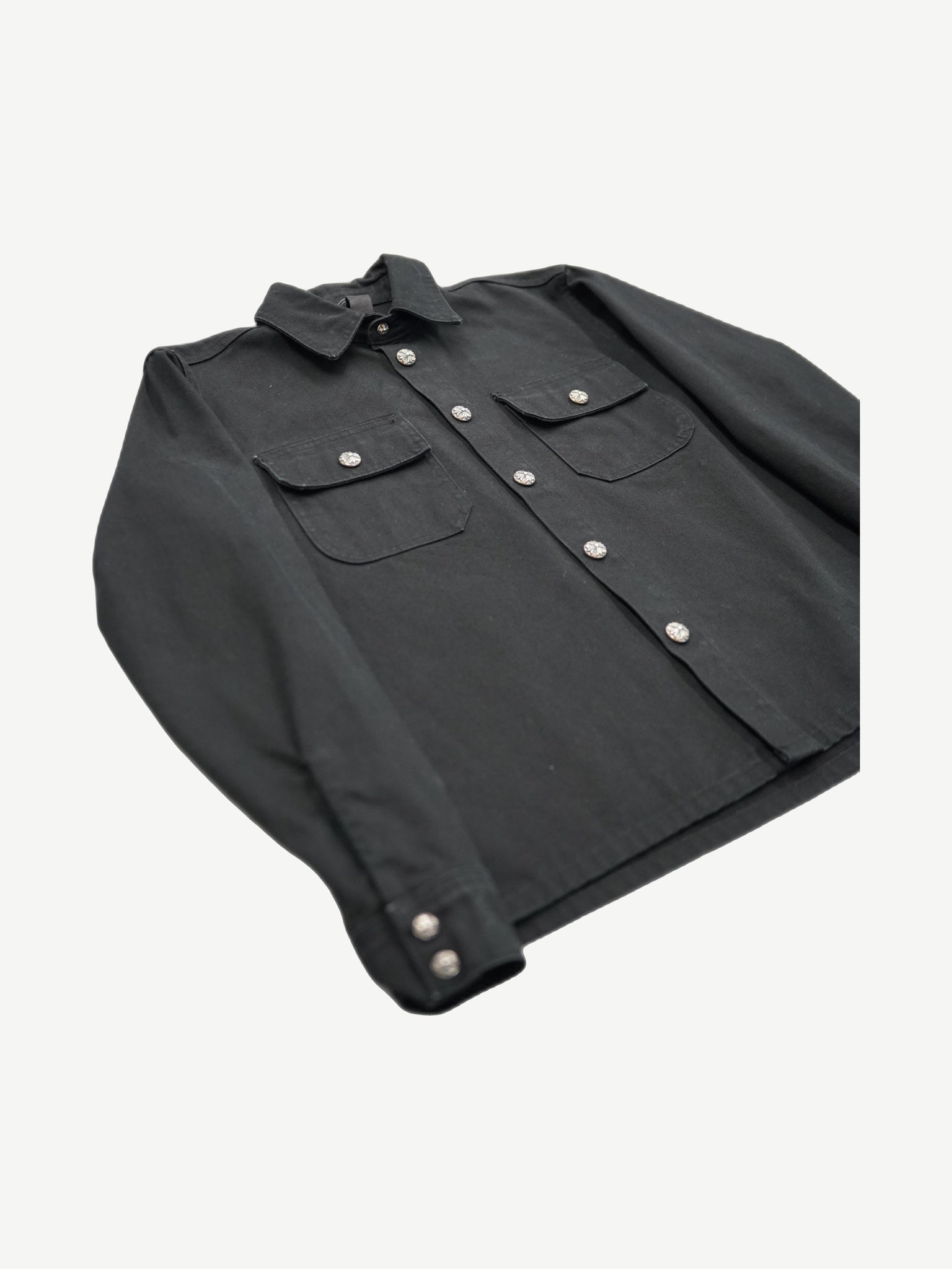 Chrome Hearts Work Dog jacket angled flat lay highlighting silver cross button placket and cuff hardware.