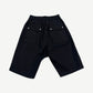 Rick Owens black Bela cargo shorts back view showing dropped seat, snap closures and tapered hem.