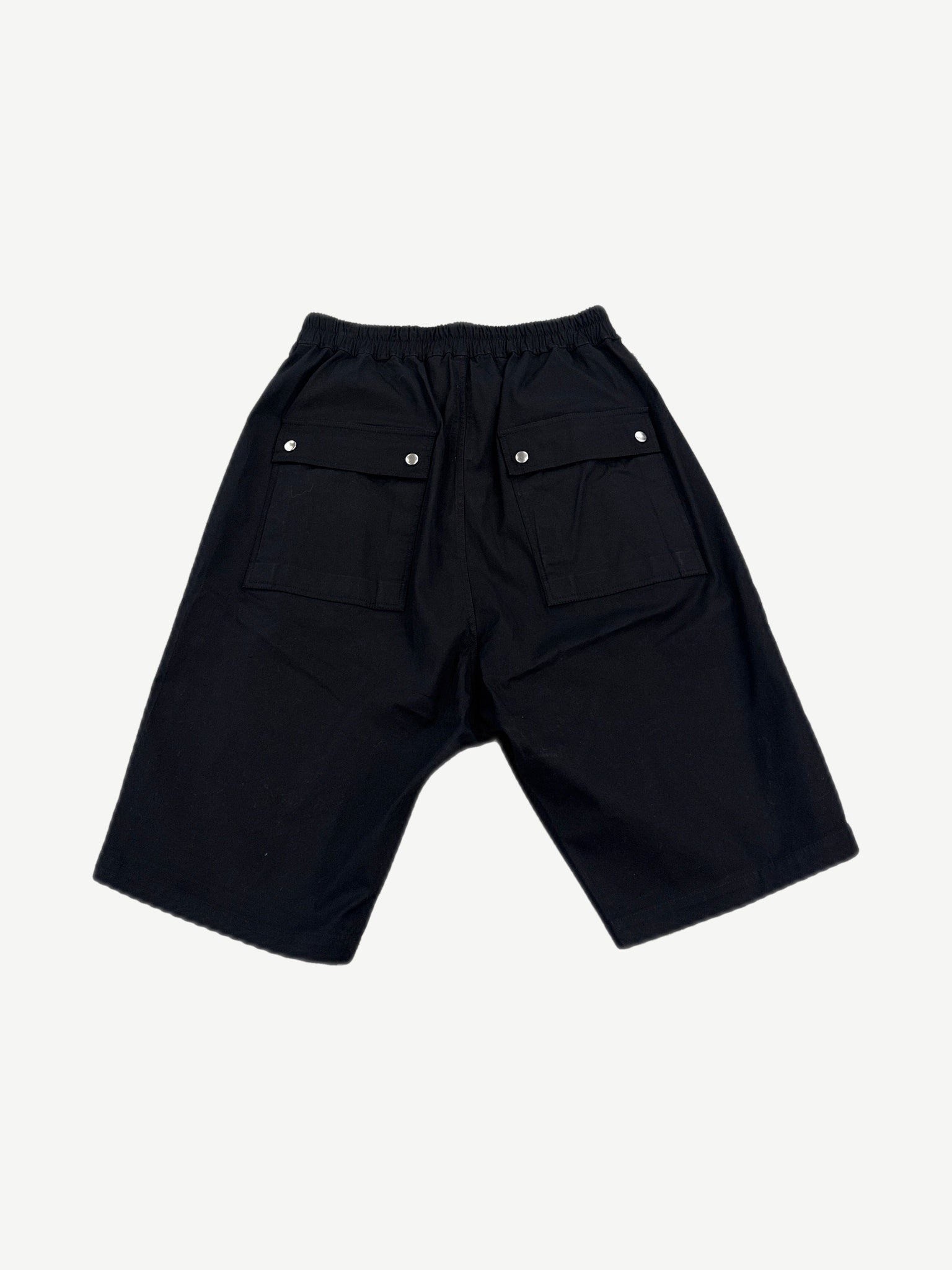 Rick Owens black Bela cargo shorts back view showing dropped seat, snap closures and tapered hem.