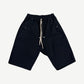 Rick Owens black Bela drop-crotch cargo shorts with drawstring waist and side snap pockets, front view.