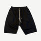 Rick Owens Bela Pods black drawstring shorts front with cream cord drawstring and zip pocket.