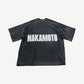 Satoshi Nakamoto Black Impact logo tee back view in sun-faded black cotton with NAKAMOTO white back print.