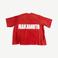Back of Satoshi Nakamoto red boxy tee with large white Nakamoto block letter print across the shoulders